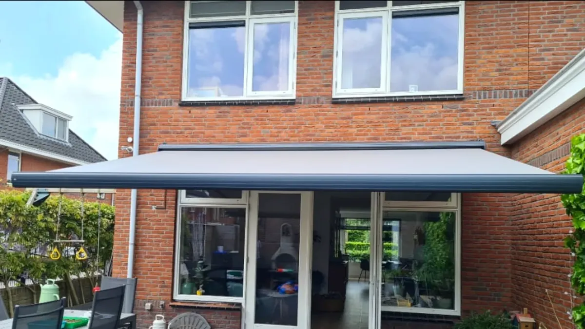 Terrasscherm van Hermann Zonwering & Montage, geplaatst aan een woning